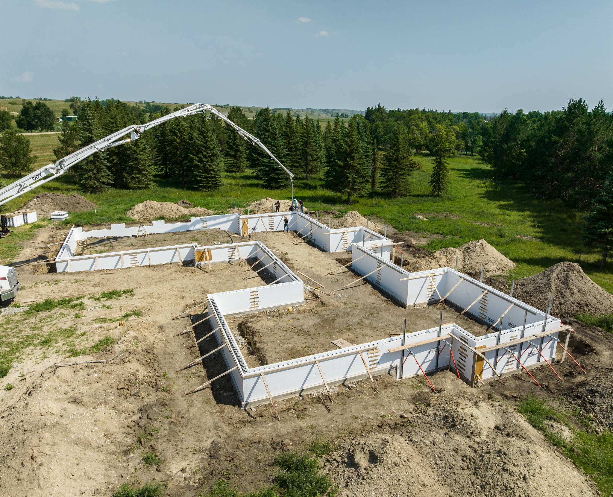Low aerial of pump boom arcing over ICF walls with crew below