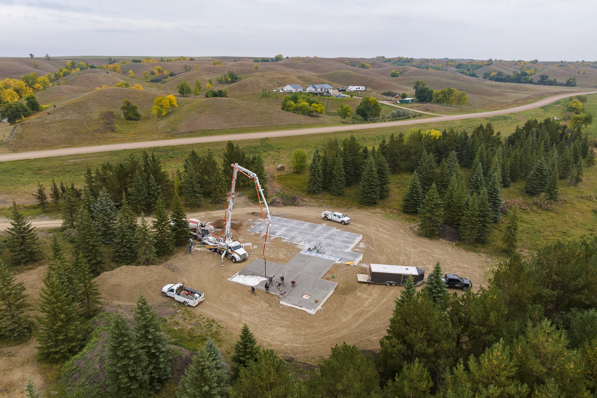 Aerial view of boom pump pouring slab with rolling hills