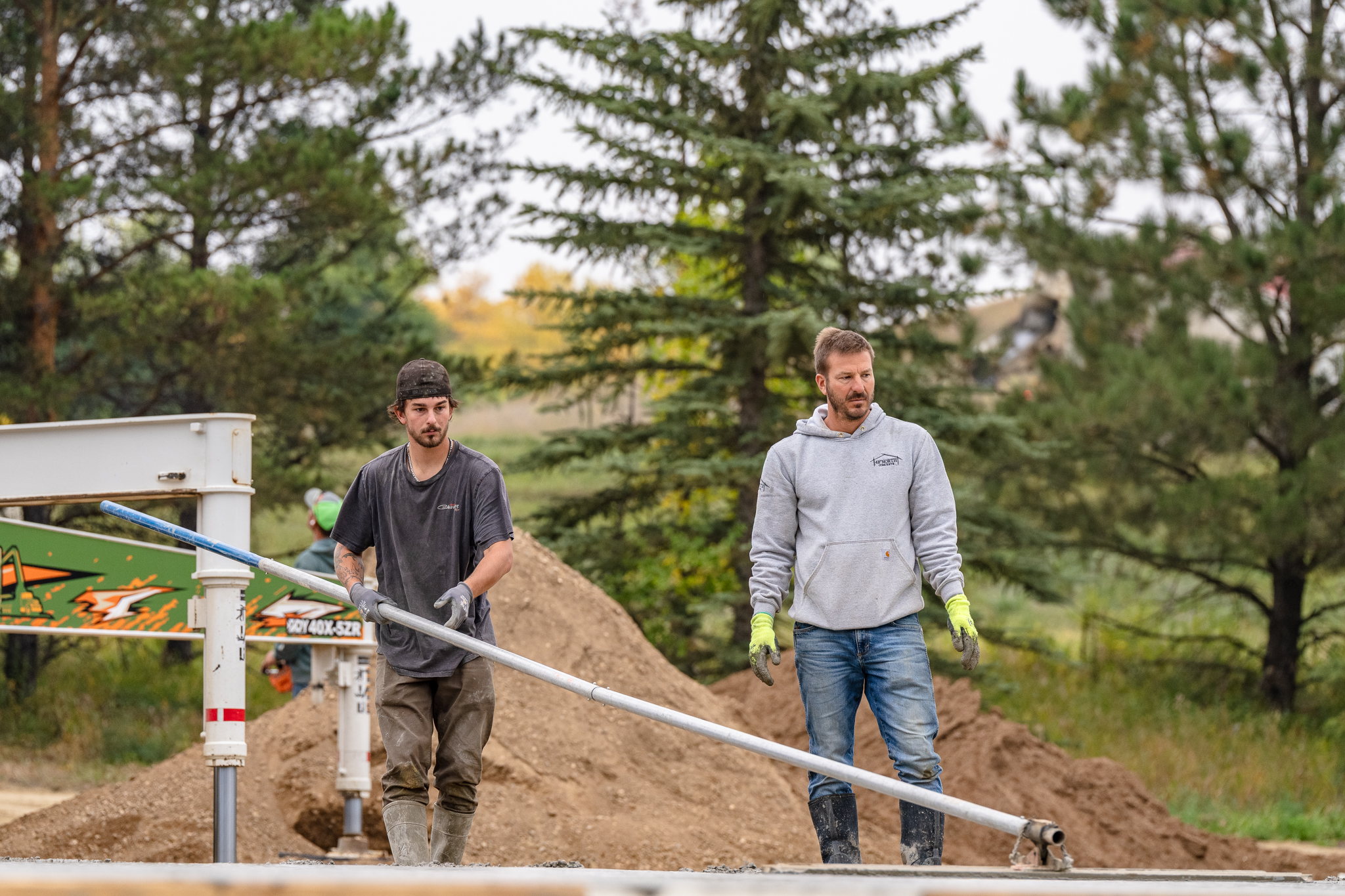 Two crew members carrying screed pipe and smiling