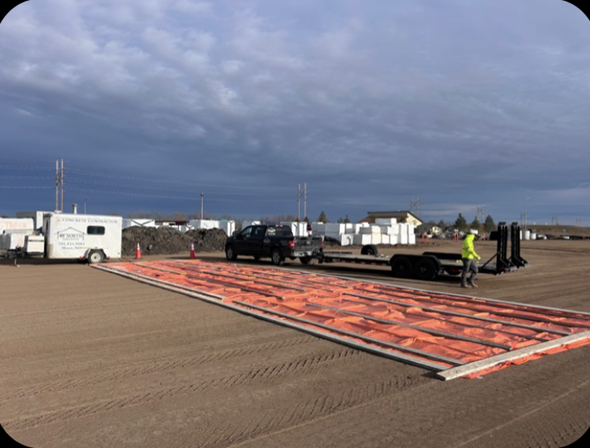 Ground thawing blankets deployed across a large concrete job site in winter